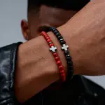 Rotes und schwarzes filigranes Kreuzarmband gemeinsam am Handgelenk