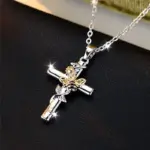 Silberfarbene Kette mit Kreuz und goldfarbener Biene auf dunklem Untergrund