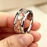 Weihnachtsring mit Weihnachtsmann und Lebkuchenmotiv zwischen Fingern gehalten
