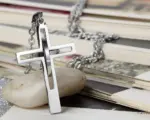 Silberfarbene Doppelkreuz Kette auf einem hellen Stein
