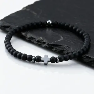 Schwarzes feines Perlenarmband mit hellem Kreuz auf Schiefer