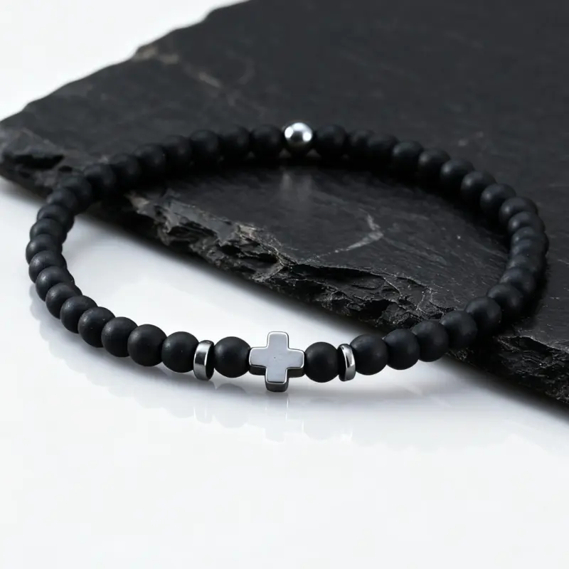 Schwarzes feines Perlenarmband mit hellem Kreuz auf Schiefer