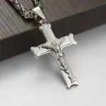 Nahaufnahme des großen Edelstahl-Kruzifixanhängers mit Jesusfigur vor Holz