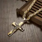 Gold-silberfarbene Byzantinerkette mit Kruzifix auf einer hölzernen Schmuckfläche