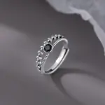 VENTFILLE Ährenring mit schwarzem Mittelstein, filigranen Blättern und offener Ringschiene vor grauem Hintergrund