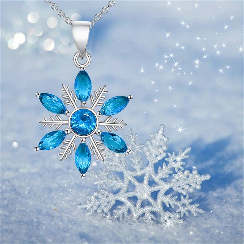 Schneekristall-Halskette mit blauen Zirkonia vor funkelnden Winterdetails