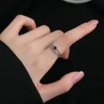 VENTFILLE silberfarbener Ring mit schwarzem Schmuckstein und Blattzweig an einer Hand getragen