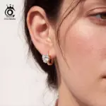 Goldfarbene ORSA JEWELS Herz-Creolen an einem Ohr im Tragebild