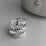 Offener BFCLUB Ring mit klarem Tropfenstein und silberfarbener gedrehter Ringschiene vor grauem Hintergrund