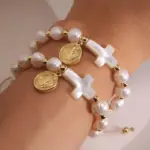 Perlenarmband mit Kreuz und goldfarbener Medaille am Handgelenk