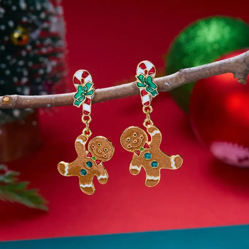 Lebkuchenmann-Ohrhänger mit goldfarbenen Details und Zuckerstangen-Stecker vor rotem Hintergrund