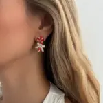 Goldfarbener Zuckerstangen-Ohrstecker mit funkelnder Schleife am Ohr getragen als Weihnachts-Schmuckbeispiel