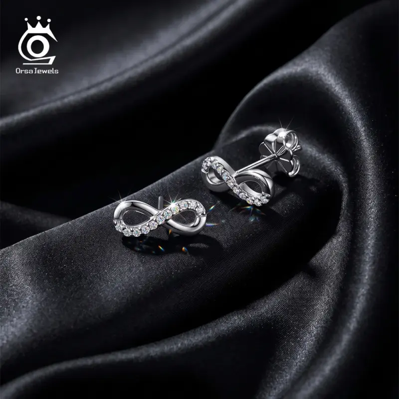 ORSA JEWELS silberfarbene Moissanit Ohrstecker mit Unendlichkeitszeichen auf dunklem Stoff