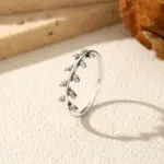 MODIAN Olivenzweig-Ring mit kleinen klaren Steinen auf hellem Stein arrangiert