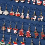 Detailaufnahme goldfarbener Weihnachts-Ohrhänger mit Schneeflocke, Rentier, Lebkuchenfigur und Zuckerstange