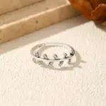 MODIAN Olivenblatt-Ring mit klaren Steinen von oben auf heller Steinoberfläche