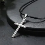 ORSA JEWELS silberfarbener Kreuzanhänger NMN01 an schwarzer Kordel auf dunkler Oberfläche – Produktfoto