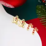 Goldfarbene Lebkuchenmann-Ohrringe neben rot-weißen Zuckerstangen-Ohrsteckern im Weihnachtsarrangement