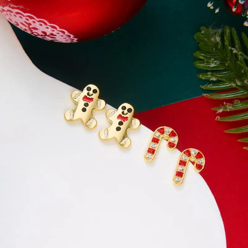 Goldfarbene Lebkuchenmann-Ohrringe neben rot-weißen Zuckerstangen-Ohrsteckern im Weihnachtsarrangement