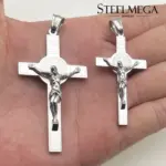 Größenvergleich der STEELMEGA Benediktus-Kruzifixanhänger in Silberoptik auf einer Hand
