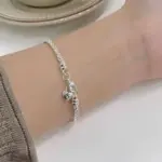 Armband mit Flechtgliedern und Herzanhänger mit Initiale S am Handgelenk