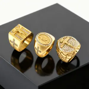 Drei PRJEWEL goldfarbene Herrenringe mit Jesuskreuz, betenden Händen und Kruzifix auf dunkler Präsentationsfläche