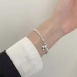 Silberfarbenes Damenarmband mit S-Herz-Charm und geflochtener Gliederstruktur im Alltag getragen
