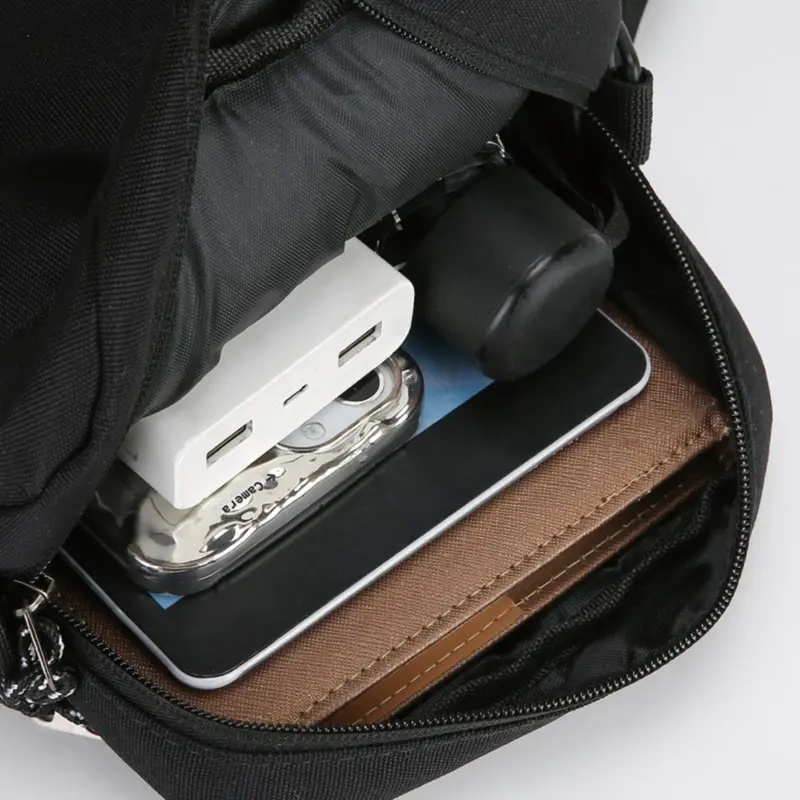 Offene schwarze Umhängetasche mit Reißverschluss, Telefon, Geldbörse und Kleinteilen als Größenbeispiel