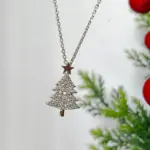 Silberfarbener Weihnachtsbaum-Anhänger mit glitzernden Zirkonia vor winterlicher Dekoration