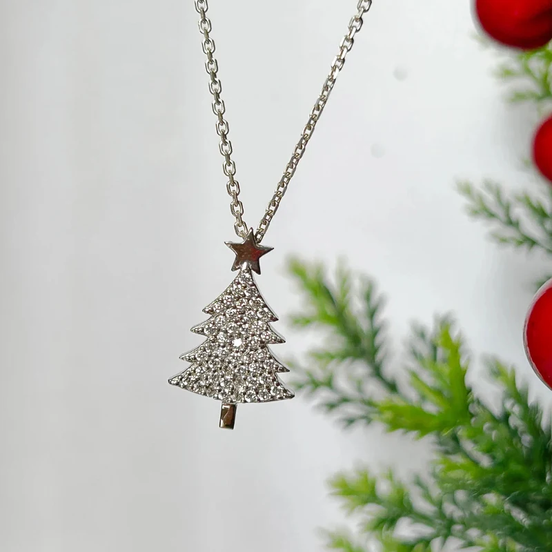 Silberfarbener Weihnachtsbaum-Anhänger mit glitzernden Zirkonia vor winterlicher Dekoration