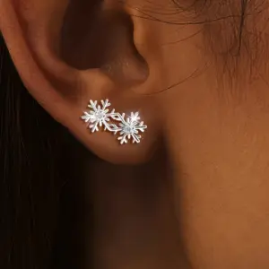 Silberfarben wirkende Huitan Doppel-Schneeflocken-Ohrstecker mit Zirkonia, am Ohr getragen