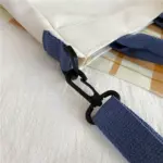 Nahaufnahme des Karabinerhakens und des abnehmbaren blauen Schulterriemens der Jesus-Tasche